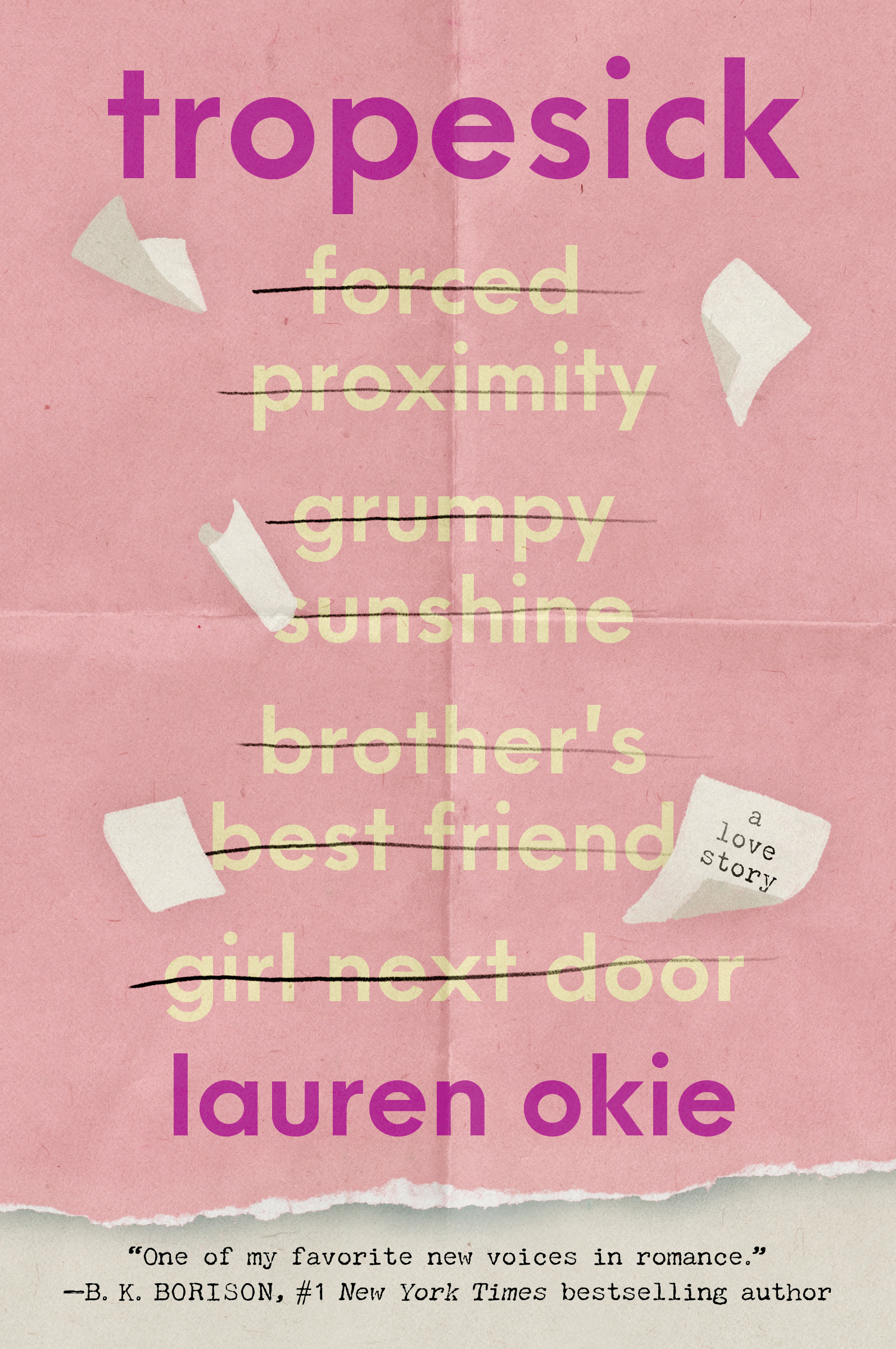 A paperback copy of Tropesick by Lauren Okie lying open on a dark velvet surface next to a flickering candle.