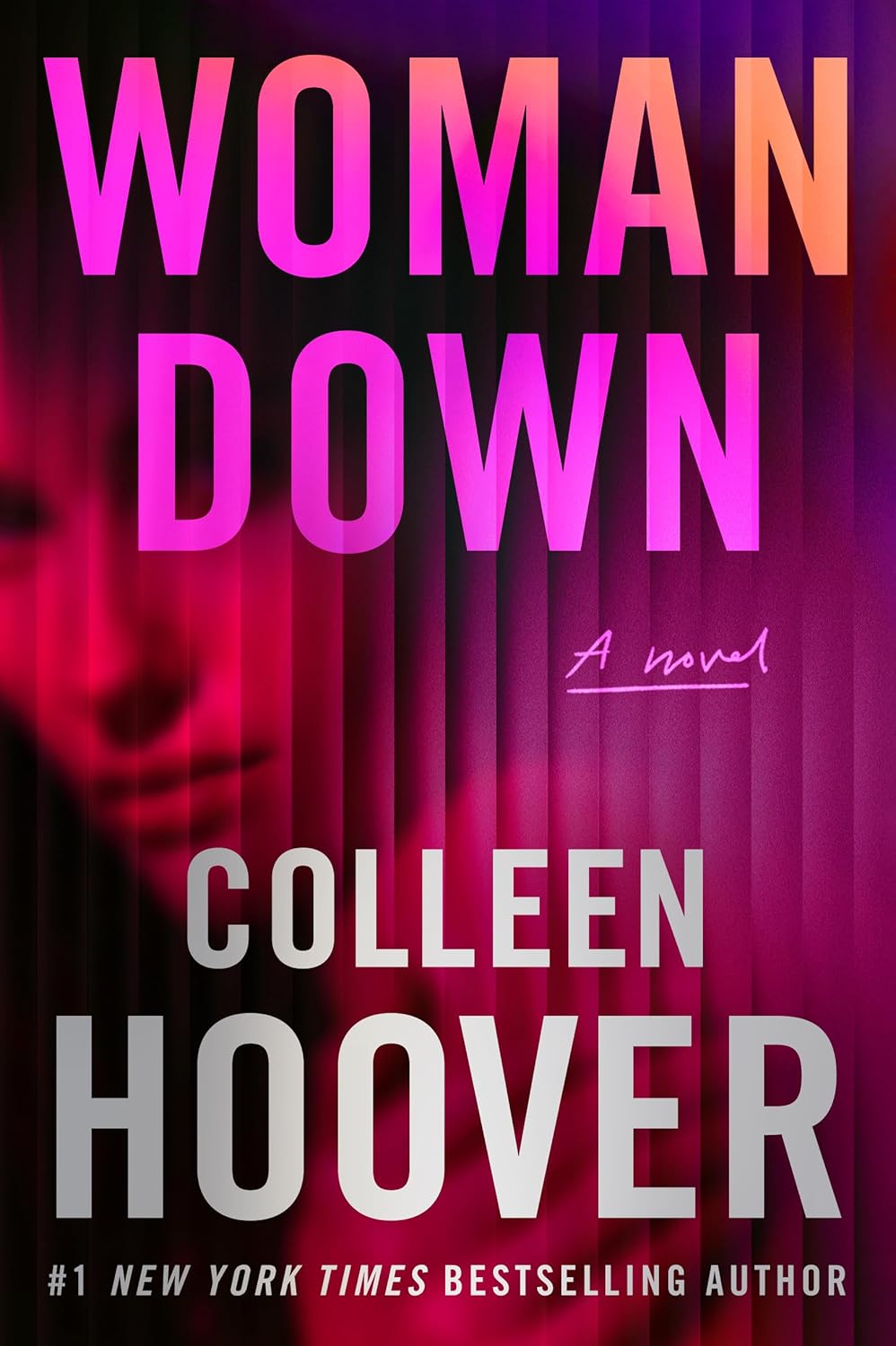 Hardcover edition of Woman Down by Colleen Hoover resting on a rustic wooden table inside a lakeside cabin.