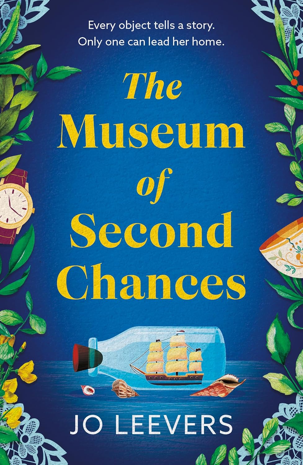 A beautifully composed hardcover copy of The Museum of Second Chances by Jo Leevers sitting on a rustic wooden table surrounded by vintage keepsake objects.